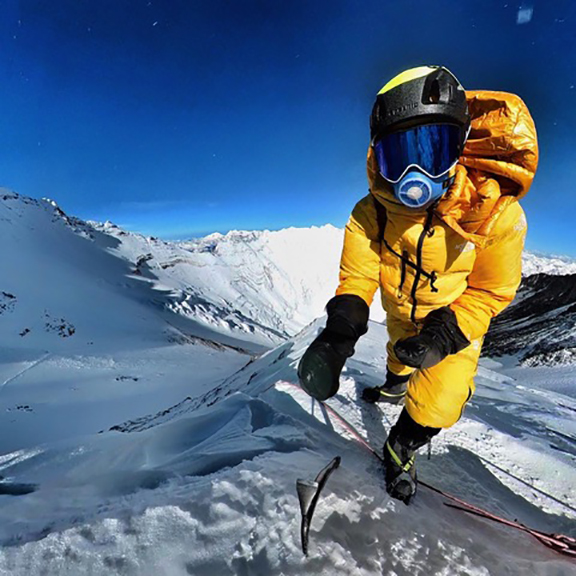 Alpinist wearing air-warming mask on high mountain.