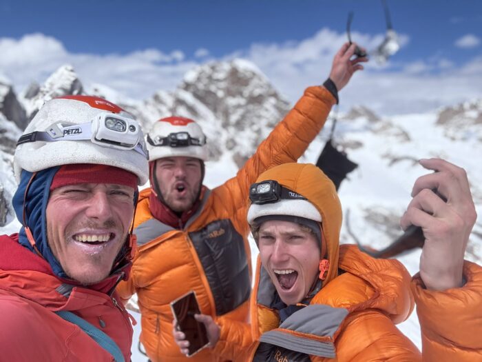 Three young climbers on a summit. 