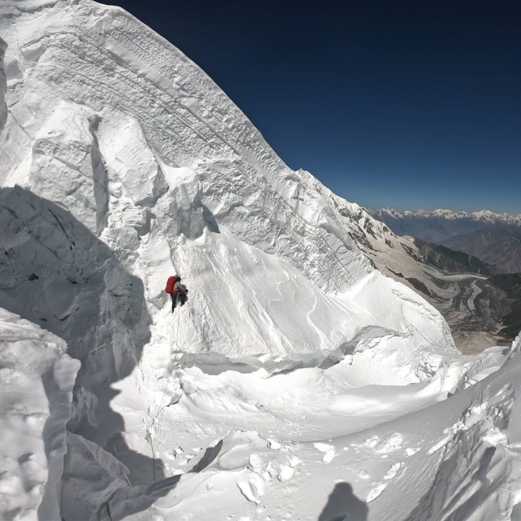A climber on a vertical seract at Diram Peak.