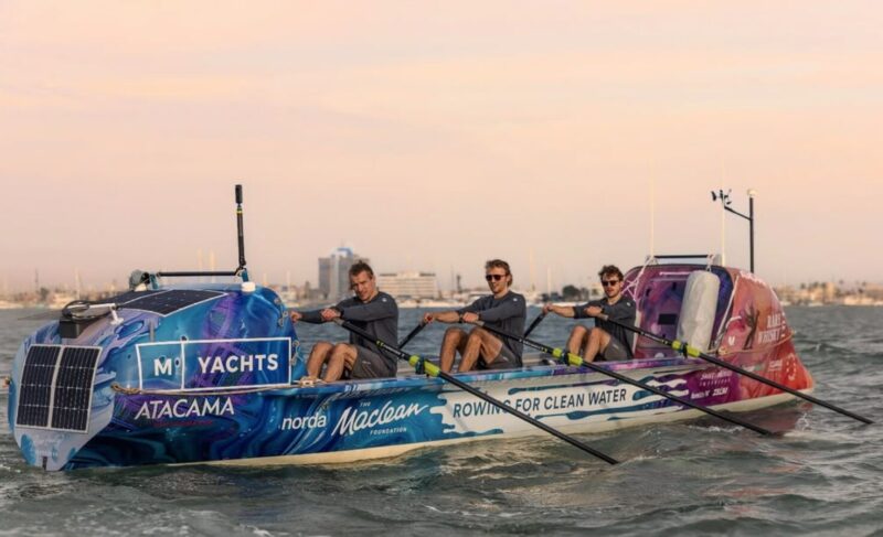 three rowers against a hazy colored sky