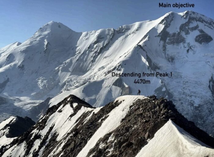 A climber on a ridge, with a much bigger mountain behind. 