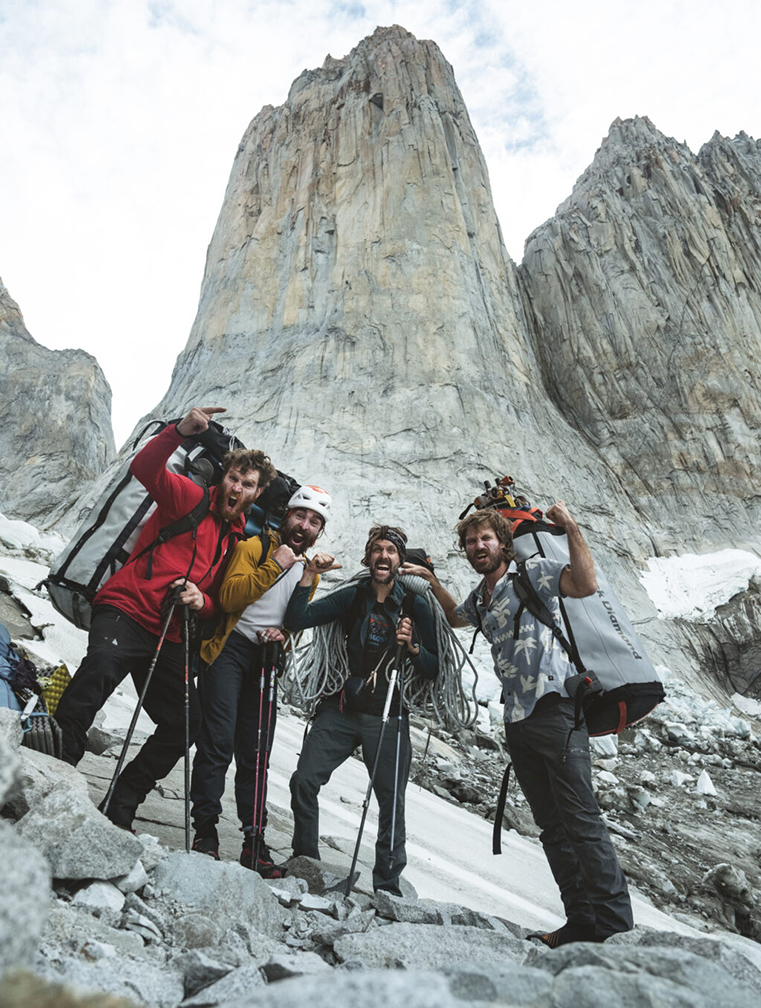 the climbers loaded with the pigs, the Torre rising behind them.